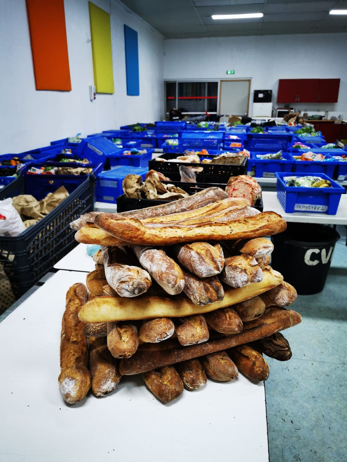 Salle de distribution avec caisses bleues remplies de légumes